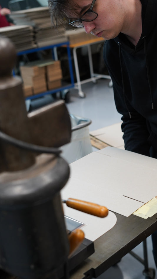 Person working with cardboard at a table in a workshop setting