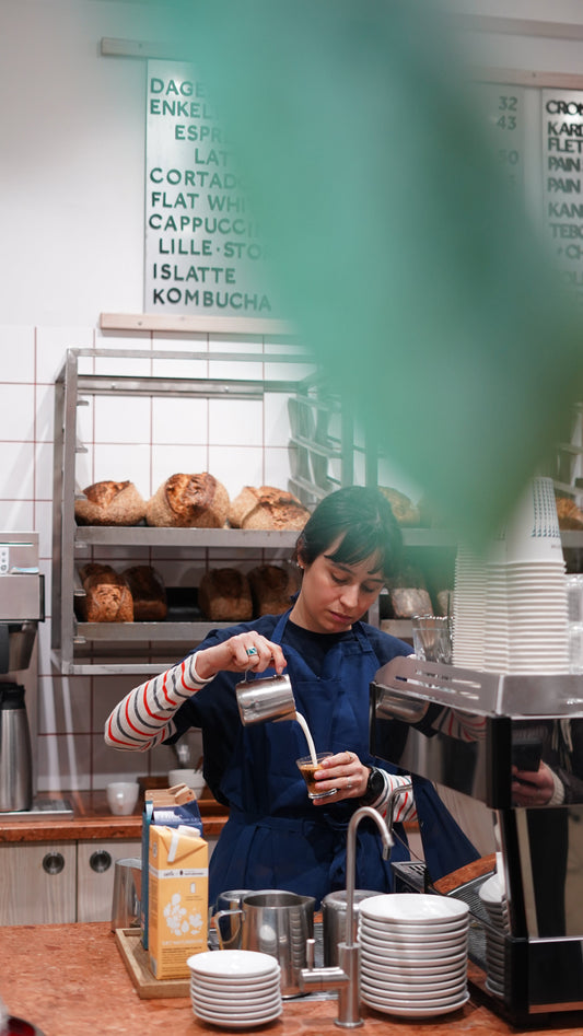 Barista pouring milk into a cup