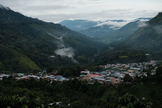 Small town nestled in a valley surrounded by mountains with mist