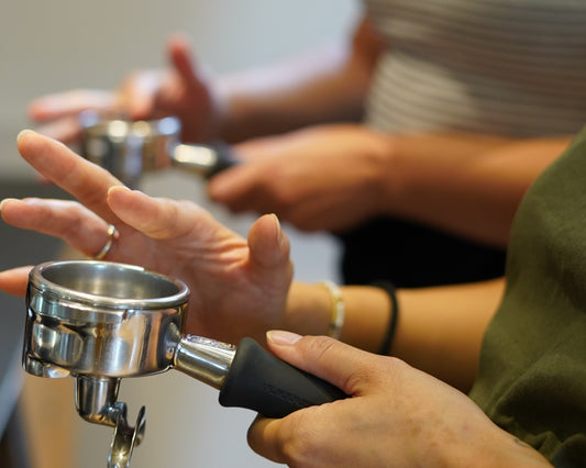 Person showing how to evenly spread coffee in an espresso group head to put in an espresso machine background